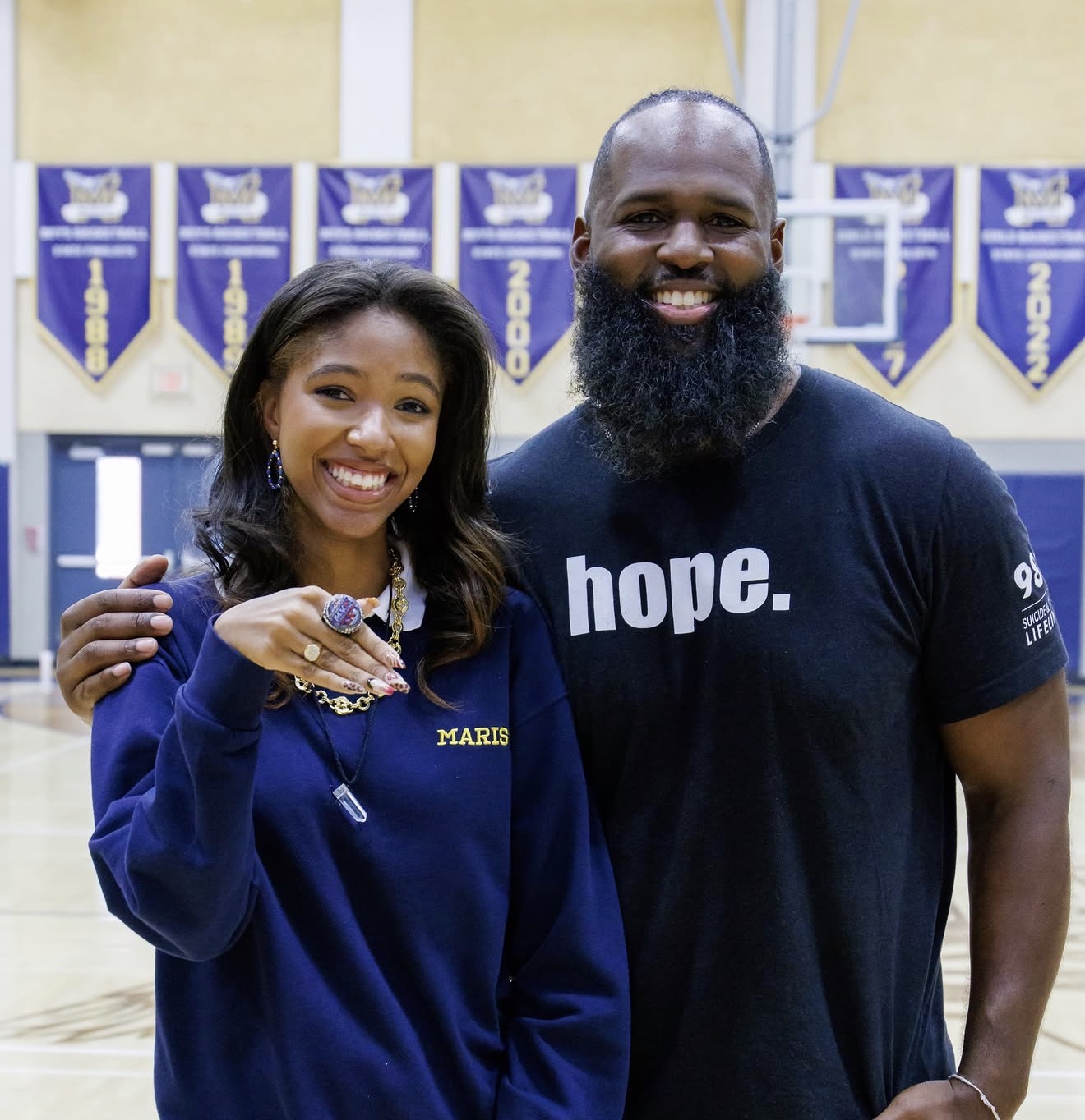Andre Fluellen with a young woman showing a Still Here championship ring